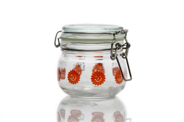 A transparent jar adorned with vibrant orange flowers sits elegantly on a white surface, showcasing its playful charm.