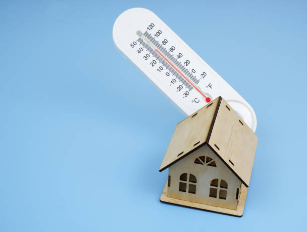 istock Wooden house model and thermometer on blue background. 2195826843