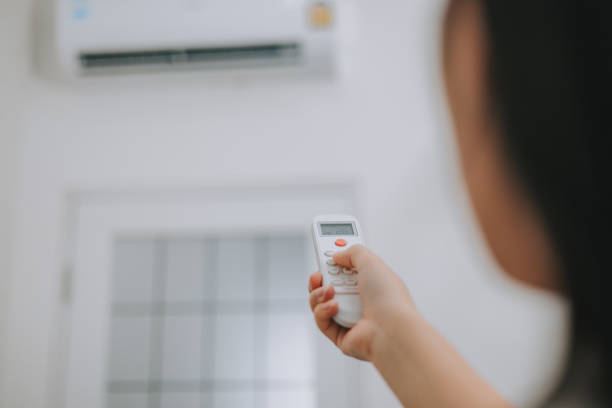 istock A woman's hand is using a remote control to adjust the temperature of the air conditioner in the room. 2195827811