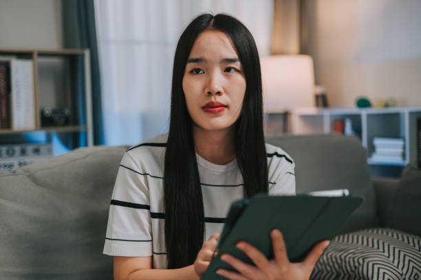 istock Asian woman controlling smart lights in room using tablet 2195827853