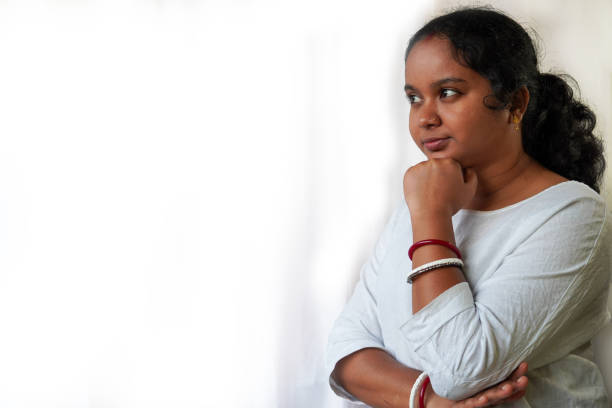 istock Young Indian woman standing over white background looking confident at the camera with crossed arms and hand raised on chin. thinking positive. 2195829127