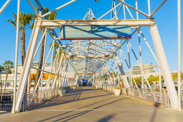 Long Beach, California - January 15, 2025: Spacious walkway with steel framework leading to the Pike Outlets, palm trees in view, bright blue sky above in Long Beach, California.