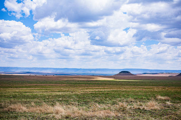 Outdoor shot of a sunny landscape with clear blue sky. Green grass and beautiful clouds in this environment. Mountain scenery.