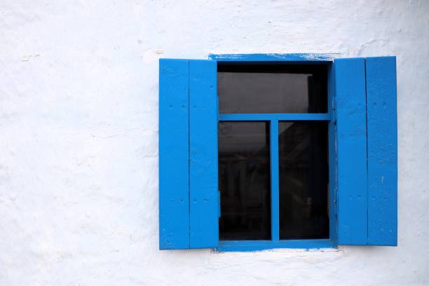 istock A Charming Blue Window with Shutters set against a Bright White Wall, creating a delightful scene 2195841565