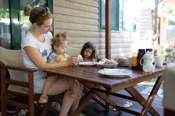 istock A woman sits on the porch with her daughters, and peeling eggs for breakfast. 2195842655
