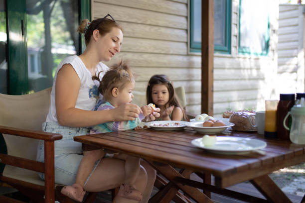 istock A woman sits on the porch with her daughters, and peeling eggs for breakfast. 2195842656