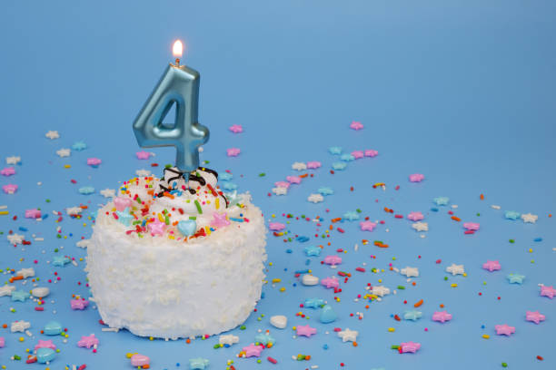 istock Coconut birthday cake on blue background with burning candle, number 4 2195842896