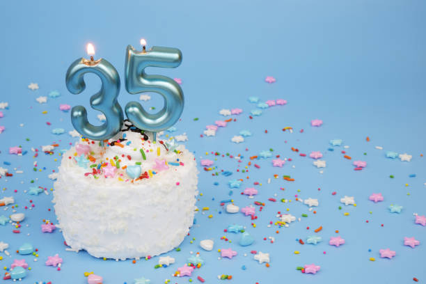 Coconut birthday cake on blue background with burning candles, number 35