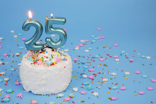 istock Coconut birthday cake on blue background with burning candles, number 25 2195843032