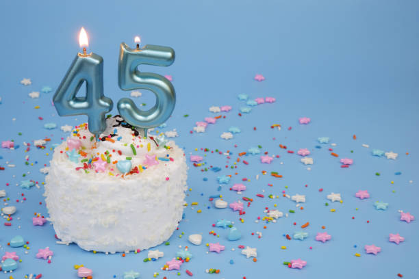istock Coconut birthday cake on blue background with burning candles, number 45 2195843048