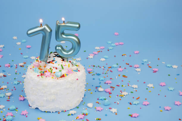 istock Coconut birthday cake on blue background with burning candles, number 75 2195843062