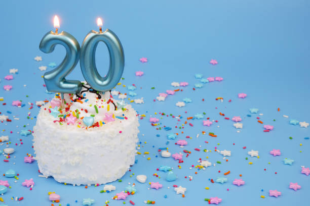 istock White coconut birthday cake on blue background with burning candles, number 20 2195843145