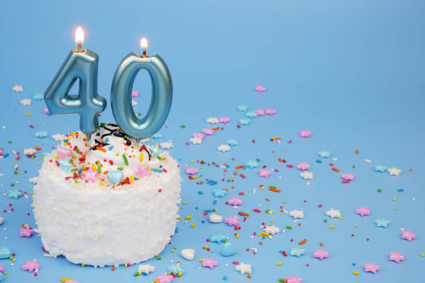 istock White coconut birthday cake on blue background with burning candles, number 25 2195843157