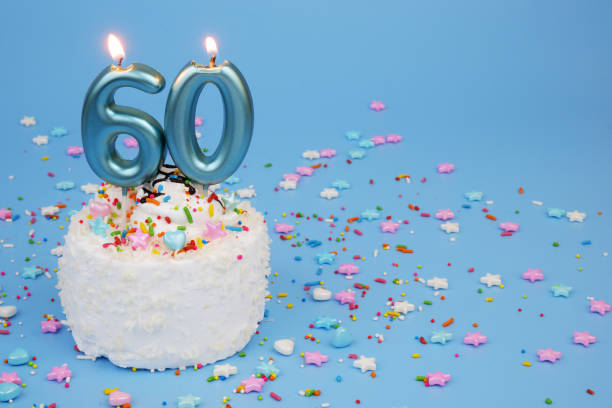 istock White coconut birthday cake on blue background with burning candles, number 60 2195843163