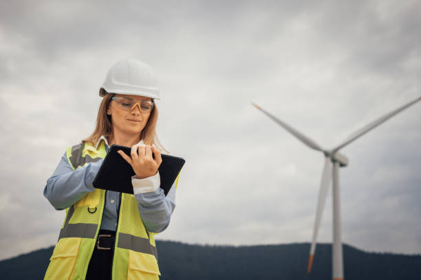 istock A skilled female engineer is actively working at a wind farm, utilizing her tablet to effectively manage various aspects of the project, ensuring smooth operations and progress tracking 2195844802