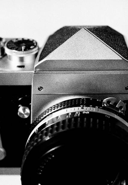 Black and white close-up image of a 1960s 35mm single-lens reflex (SLR) professional film camera with a 50mm fast f/1.4 prime lens. Cameras like this was very advanced cameras of its day and used by many photojournalists. The image was captured on analog (analogue) black and white Ilford Delta 400 film. The granularity is real film grain. The negative has been scanned by a high resolution film scanner. Minimal post processing.