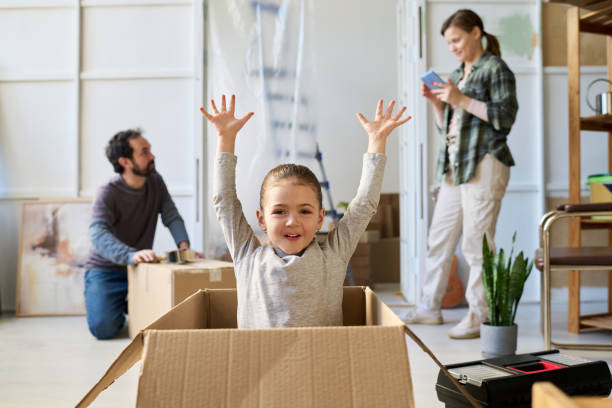 istock Girl raising arms while sitting in box 2195847515