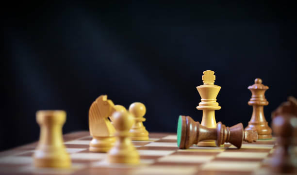 istock Dramatic end, final move in chess, check mate, brown king chess piece fallen down defeated, over black background for concepts Checkmate, loss, Strategy and tactics, Triumph, Power shift after war or battle 2195847960