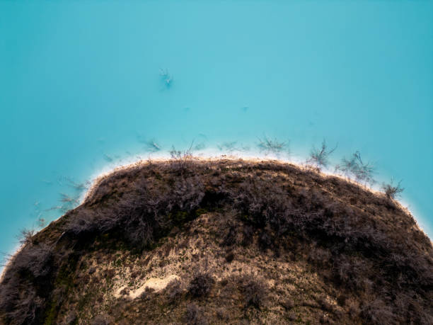 istock A striking contrast between turquoise water and dark, rugged terrain at a tailings lake. The industrial site reveals layers of environmental impact, blending sharp textures with vivid colors 2195851985