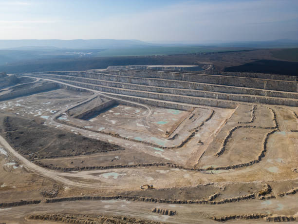istock An open-pit quarry with terraced layers and heavy machinery operating on the dusty terrain. The industrial site highlights large-scale excavation processes and environmental transformation 2195852012