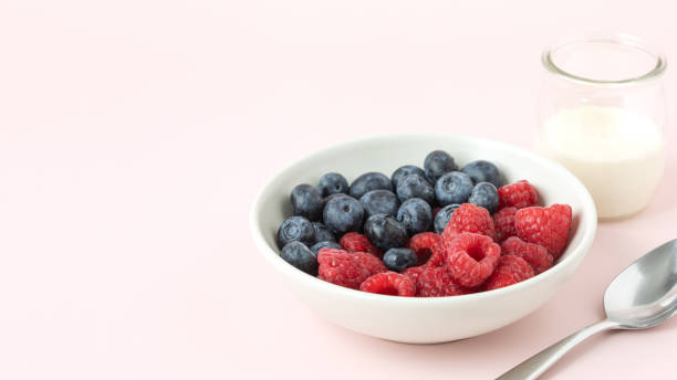 Berries in the bowl, spoon and glass of milk