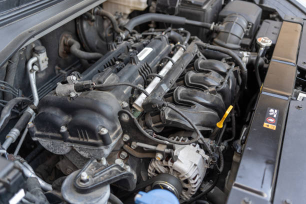 istock A car engine bay with various components including the intake manifold, hoses, wiring, and fluid reservoirs. The engine appears to be a modern internal combustion engine. 2195861524