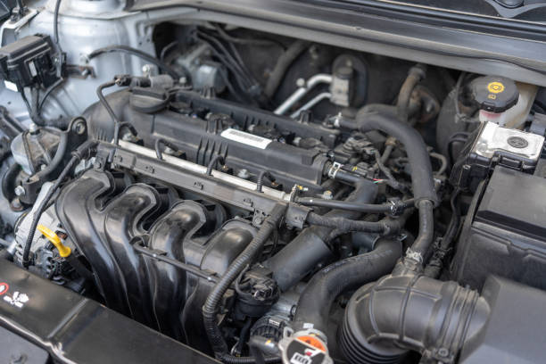istock A car engine bay with various components including the intake manifold, hoses, wiring, and fluid reservoirs. The engine appears to be a modern internal combustion engine. 2195861534