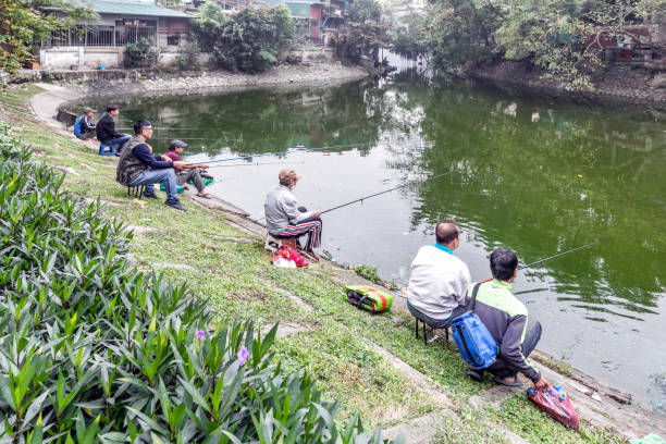 An Asian elementary school student is fishing in a pond