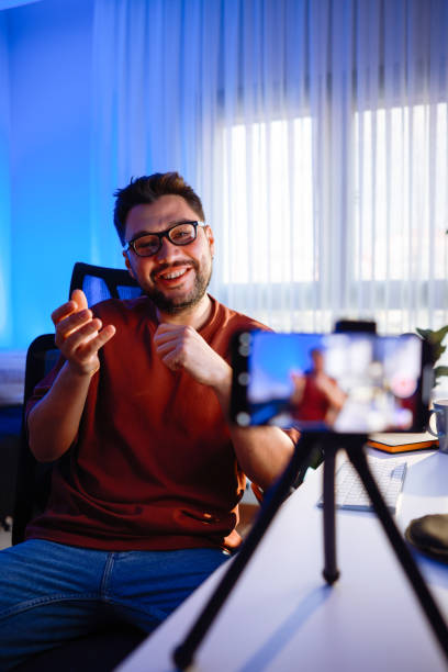 istock Male blogger unboxing parcel with tech product using smartphone on tripod, recording video content for tech blog at home 2195868929