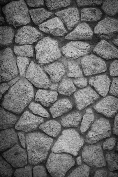 Empty monochrome black and white (dark gray) embossed stone wall for abstract background and texture for interior or exterior design. Beautiful patterns, space for work, banner, wallpaper close up.Vertical.