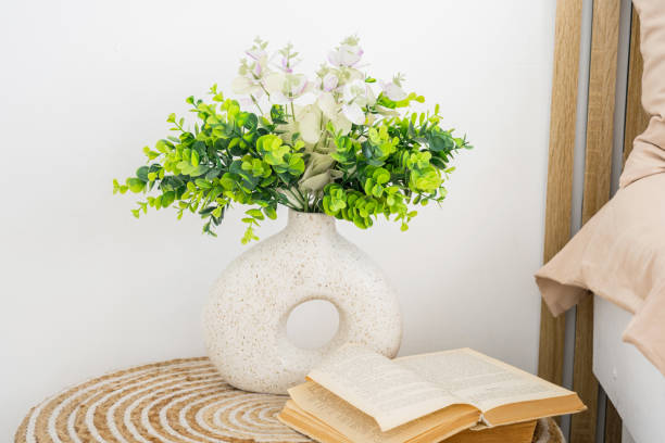 istock Decorative vase with plants beside an open book on a nightstand 2195875789