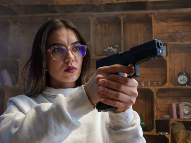 istock A young woman using a gun to protect herself. 2195884176