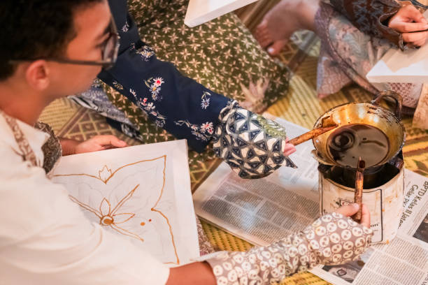 The three friends, all dressed in traditional batik attire, are full of joy as they engage in the Batik workshop. Their expressions capture the excitement and camaraderie of learning a new cultural craft together.