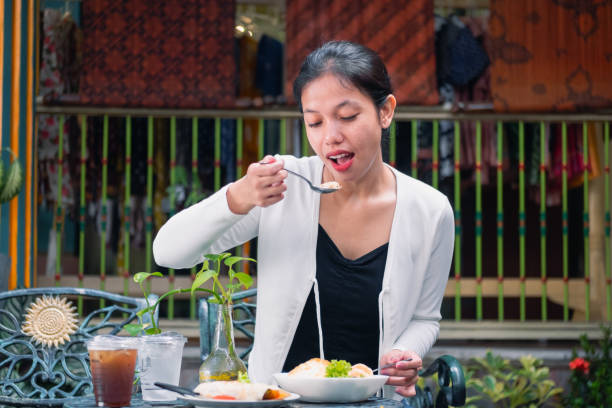 The traveler enjoys a hearty plate of nasi goreng, immersing herself in the rich taste of a beloved local dish.
