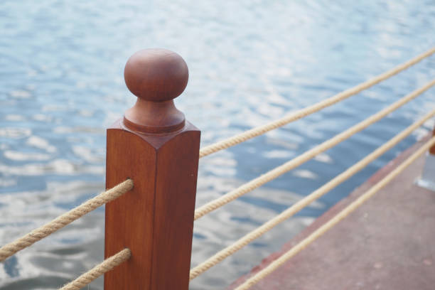 A wooden post featuring a rounded top, secured firmly by rope, positioned beside calm water