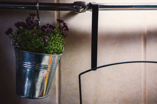 Decorative flowers in a metal bucket hanging on a bar in the kitchen, as a decoration and fragrant detail.
