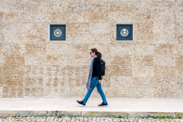 istock woman walking past a modern tiled exterior wall 2195905784