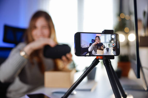 istock Female blogger unboxing parcel with tech product using smartphone on tripod, recording video content for tech blog at home 2195908824