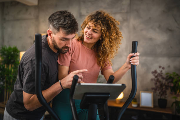 istock woman exercise on elliptical machine and follow training on tablet 2195910726
