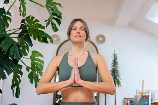 istock Young woman meditating while doing yoga in a bright home setting 2195916446