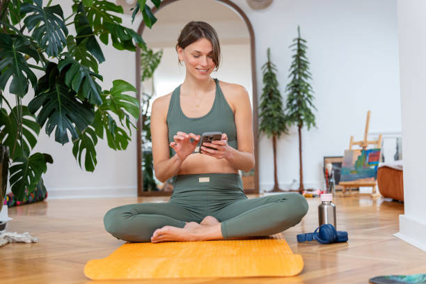 istock Young woman resting during yoga practice at home and using her smartphone 2195916530