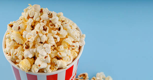 istock Classic red striped popcorn cardboard cup on blue background 2195918780
