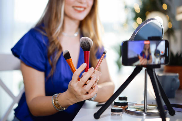 istock Young women using social media shoots makeup video in her room 2195923489
