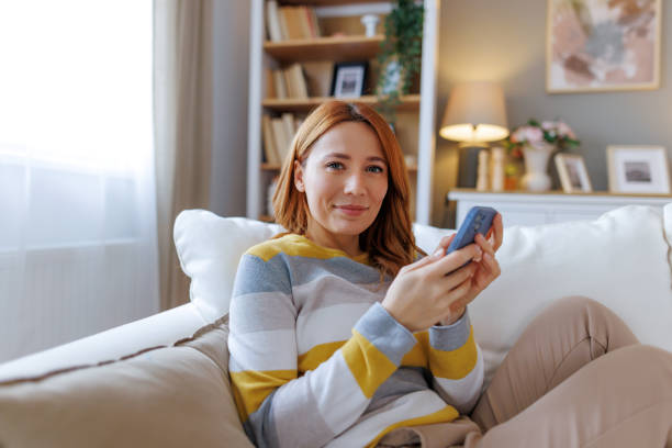istock Young woman relaxing on sofa using smartphone at home 2195924082