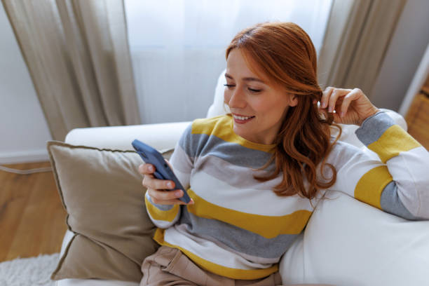 istock Woman relaxing on sofa using mobile phone at home 2195924108