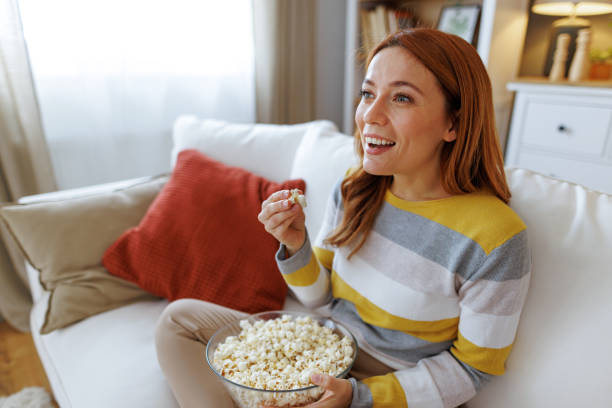 istock Woman enjoying popcorn while watching tv on the sofa at home 2195924197