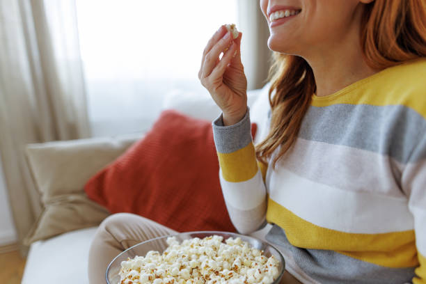istock Smiling woman enjoying popcorn on the sofa at home 2195924201
