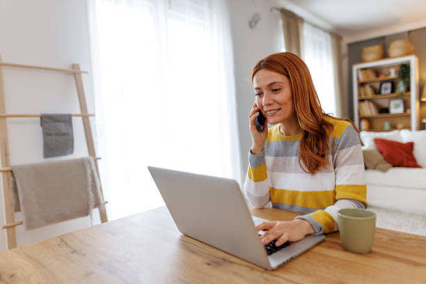 istock Woman working from home talking on phone and using laptop 2195924287