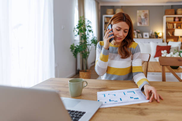 istock Businesswoman working from home talking on the phone and analyzing charts 2195924328