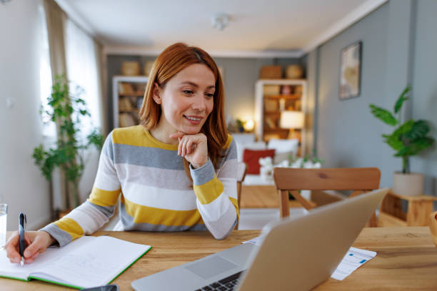 istock Young woman working from home attending online meeting and taking notes 2195924358